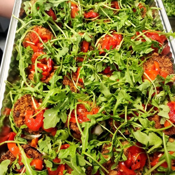 Close-up of Stallone's Italian Eatery's eggplant parmesan, topped with fresh arugula and diced tomatoes.