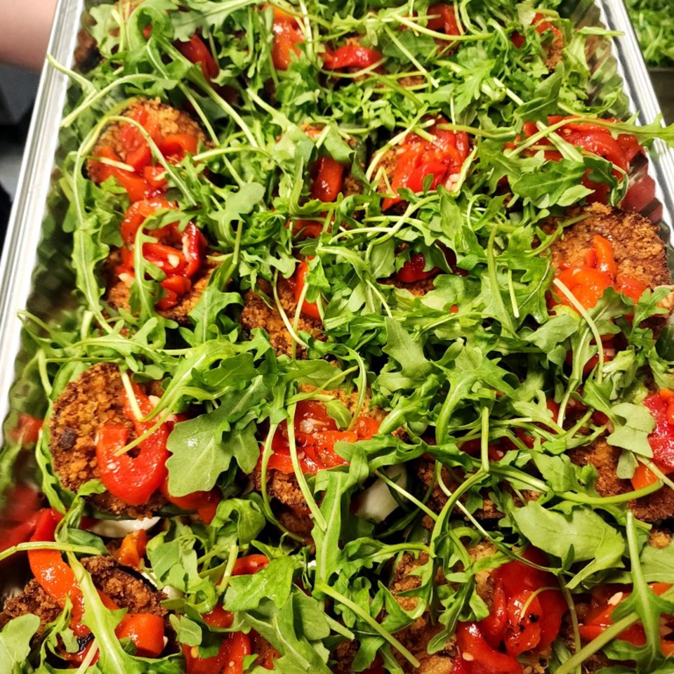 Close-up of Stallone's Italian Eatery's eggplant parmesan, topped with fresh arugula and diced tomatoes.