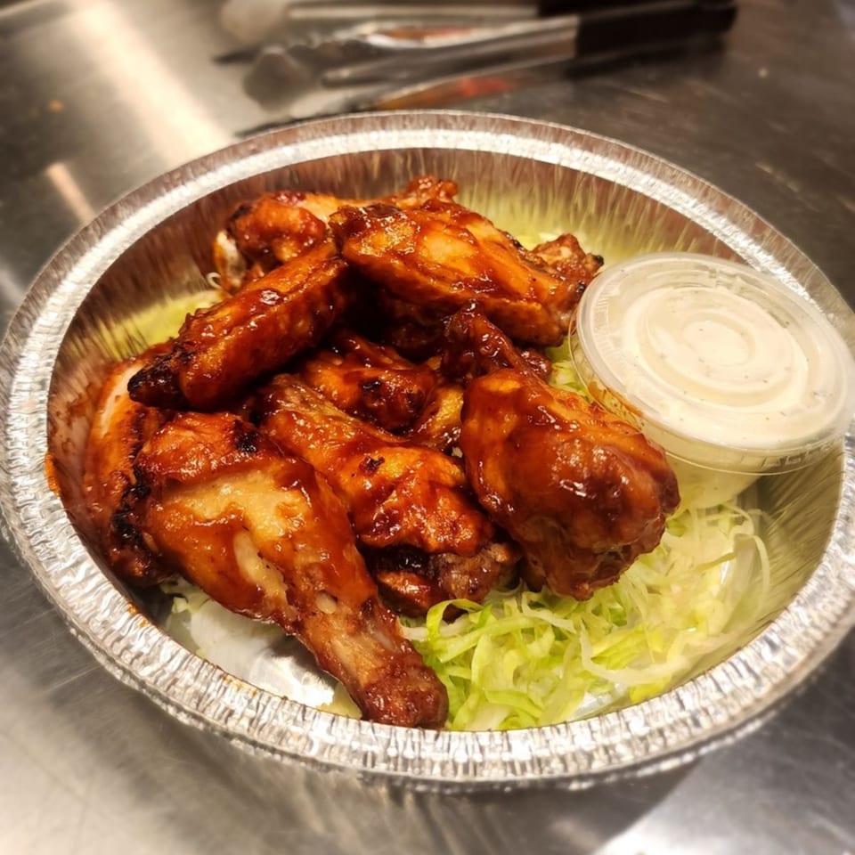 Stallone's Italian Eatery's BBQ chicken wings with shredded lettuce and a side of ranch dressing.